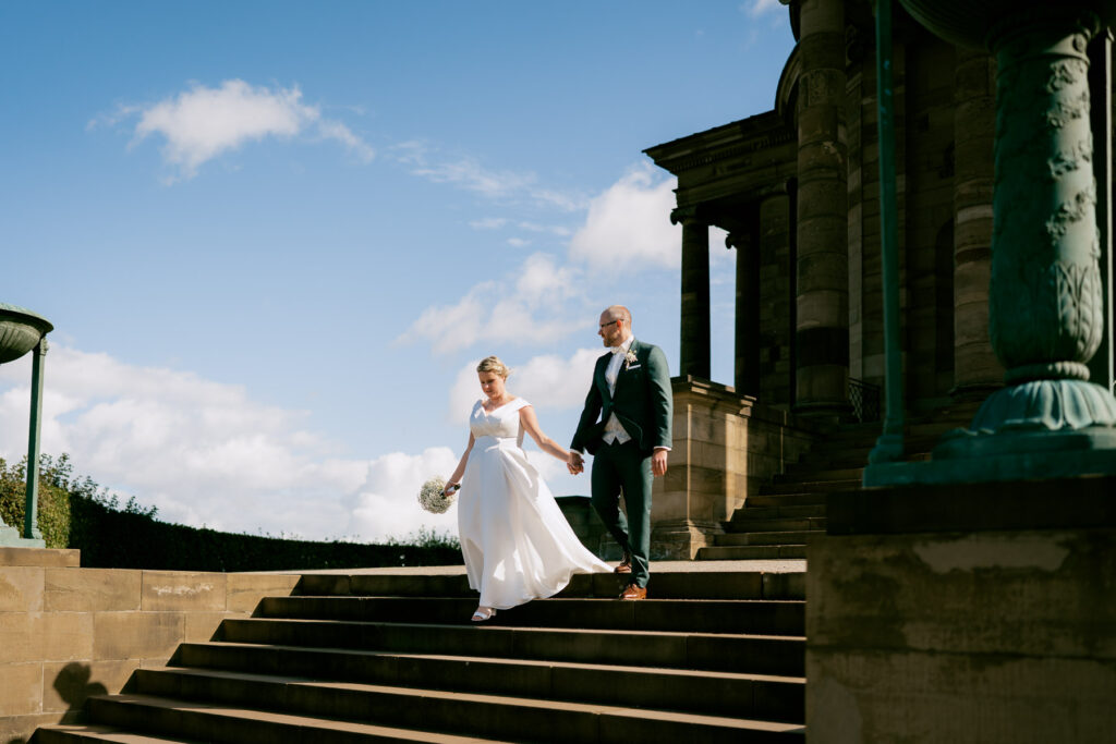Hochzeitsfotograf Stuttgart: Brautpaar läuft Hand in Hand an der Grabkapelle entlang