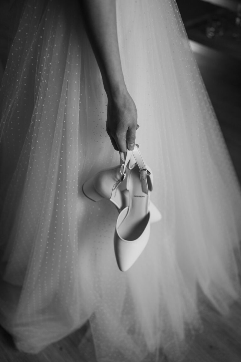 Braut hält ihre Schuhe in der Hand beim Getting Ready Shooting